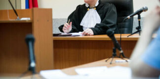 Judge at desk in courtroom with microphones visible