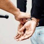 Person in handcuffs being arrested by police officer