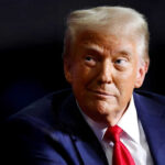 Person wearing suit and red tie looking sideways