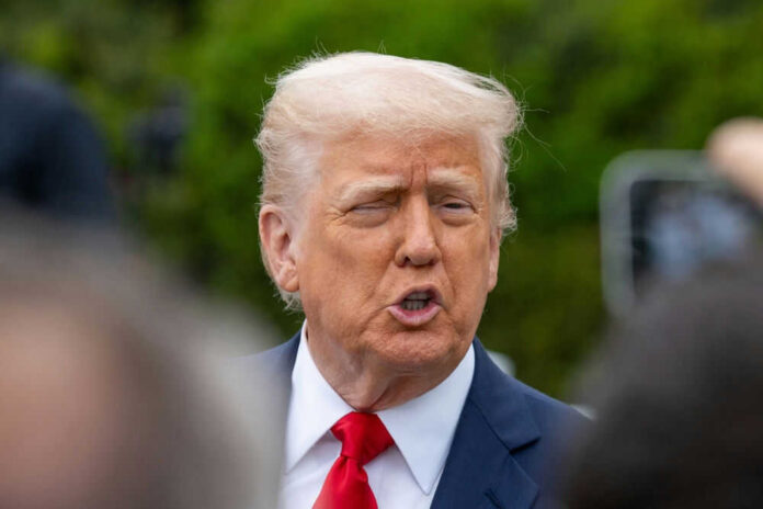 Person in suit talking outdoors with trees background
