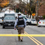 Law enforcement officer walking towards a crime scene marked by police tape