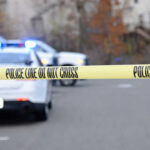Police tape blocking road with parked police vehicles