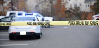 Police tape blocking road with parked police vehicles