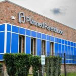 Brick building with blue windows and logo signage