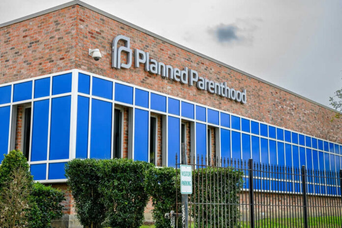 2435160787 Brick building with blue windows and logo signage