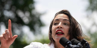 Person speaking passionately at outdoor event with microphones