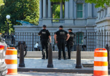 Three police officers in dark uniforms standing outside building
