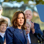 Woman speaking at podium with audience behind her