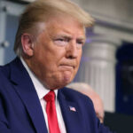 Man in suit and red tie looks serious
