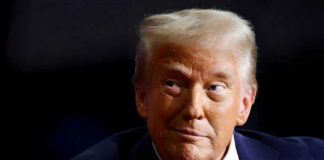 Person wearing suit and red tie looking sideways