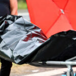 Person carrying body bag on stretcher outdoors
