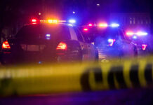 Police cars with flashing lights behind caution tape