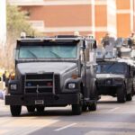 Military vehicles and personnel in a parade on a city street