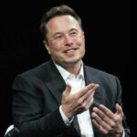 Smiling man gesturing while sitting wearing a suit