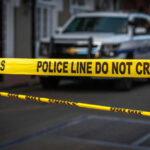 Yellow police tape in front of blurred vehicles