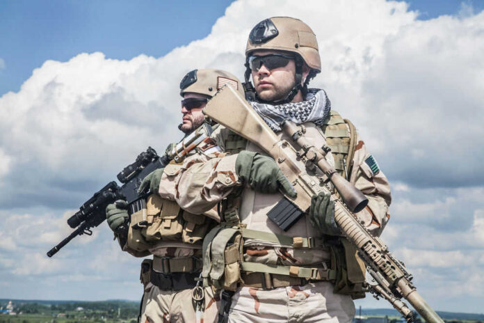 Two soldiers in desert camouflage holding rifles