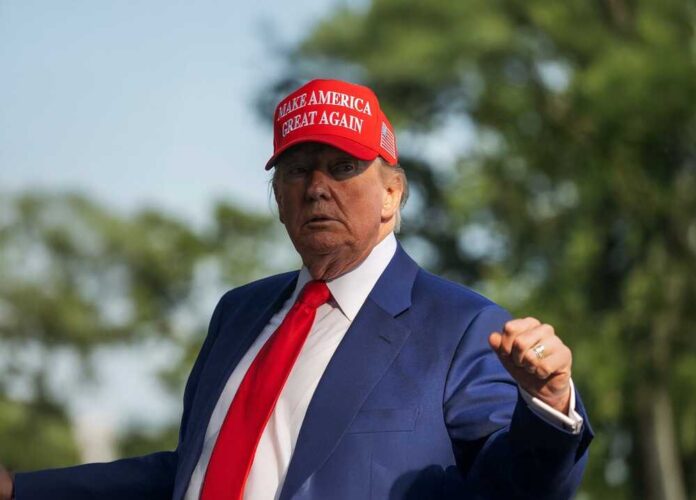 Man in a blue suit and red tie wearing a red cap with text