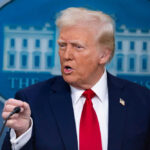 Man in suit speaking at a press briefing